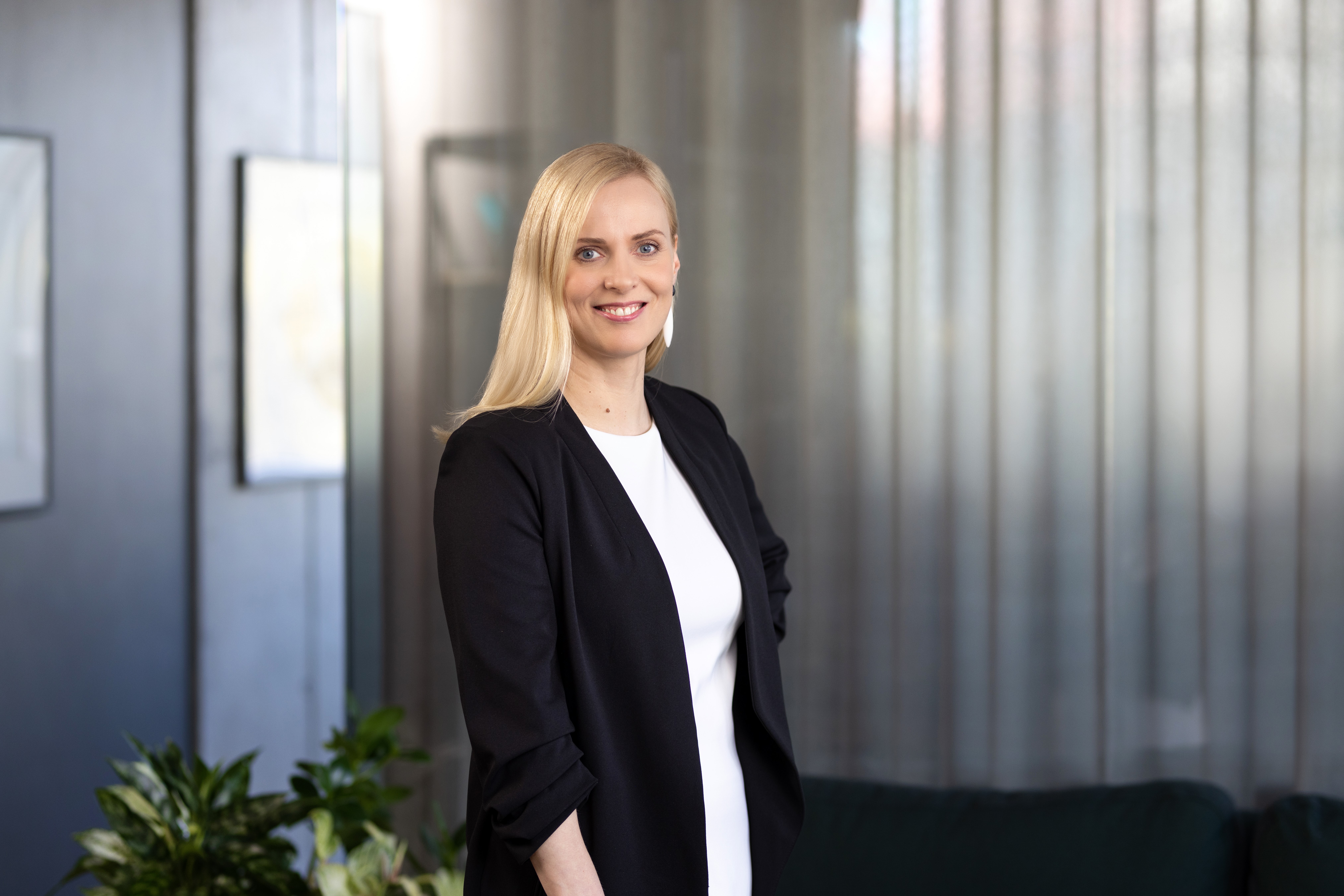 Улыбающаяся женщина стоит в офисном помещении.