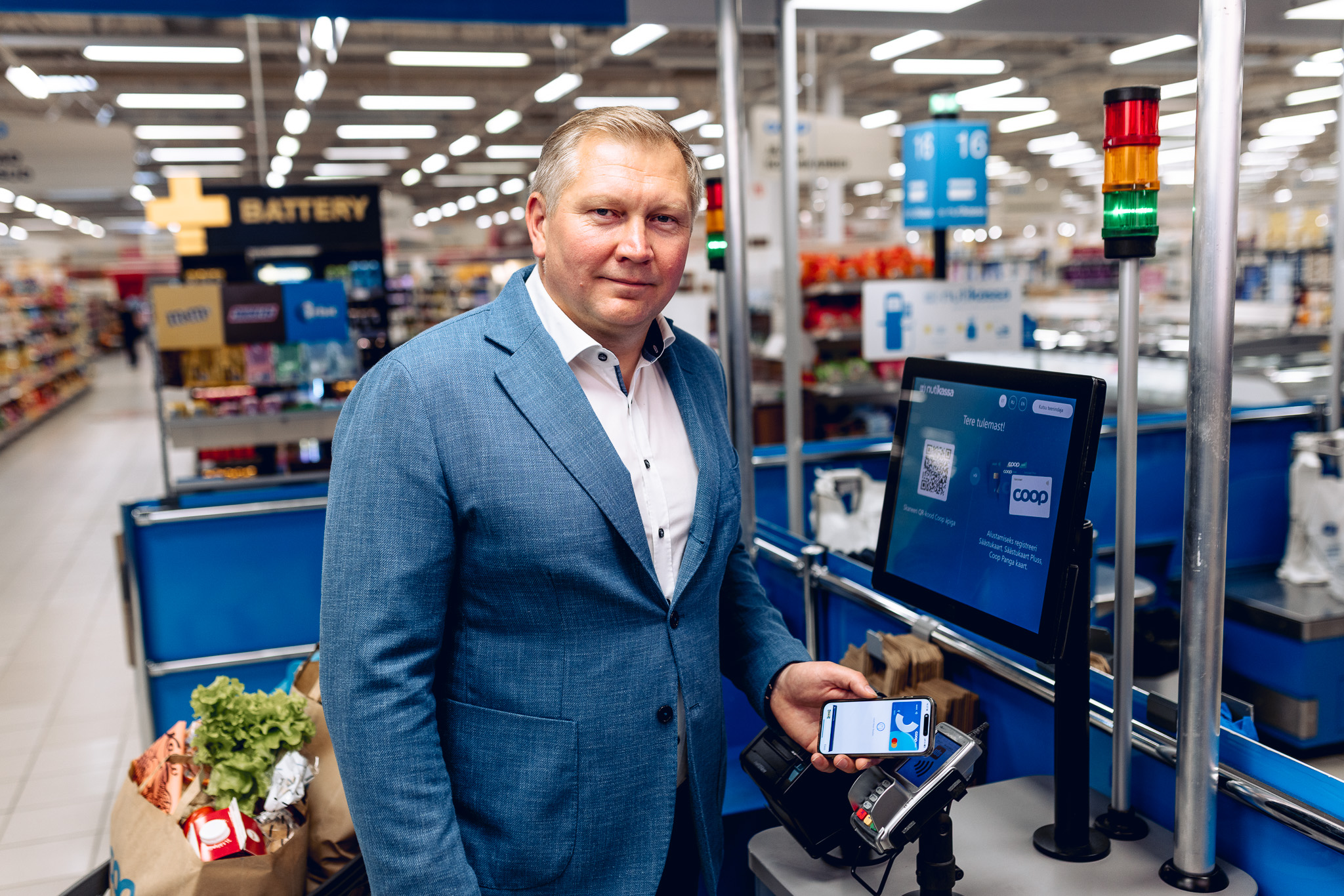 Mees maksab nutitelefoniga poes iseteeninduskassas.