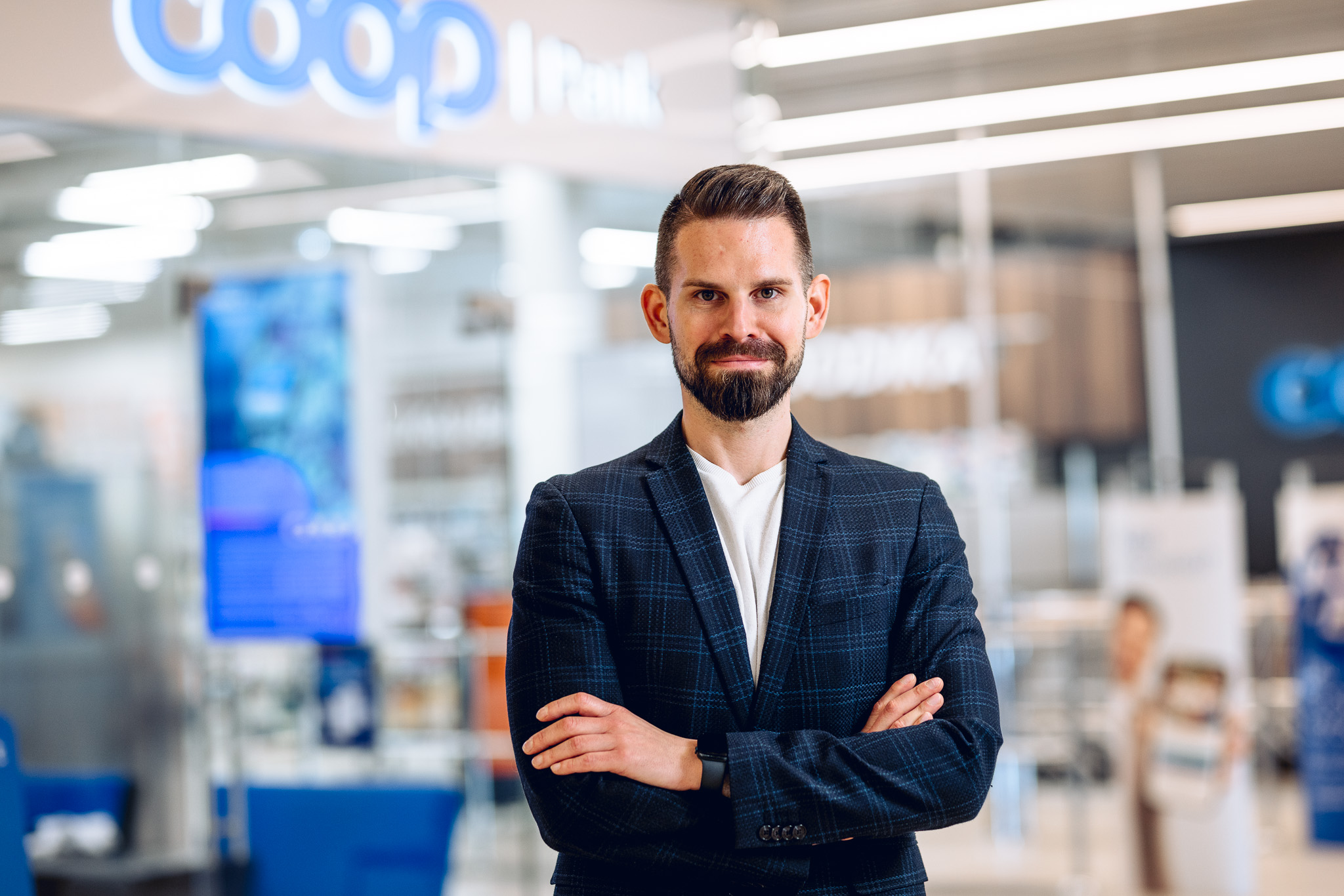 Habemega mees pintsakus seisab ristatud kätega pangakontori ees.