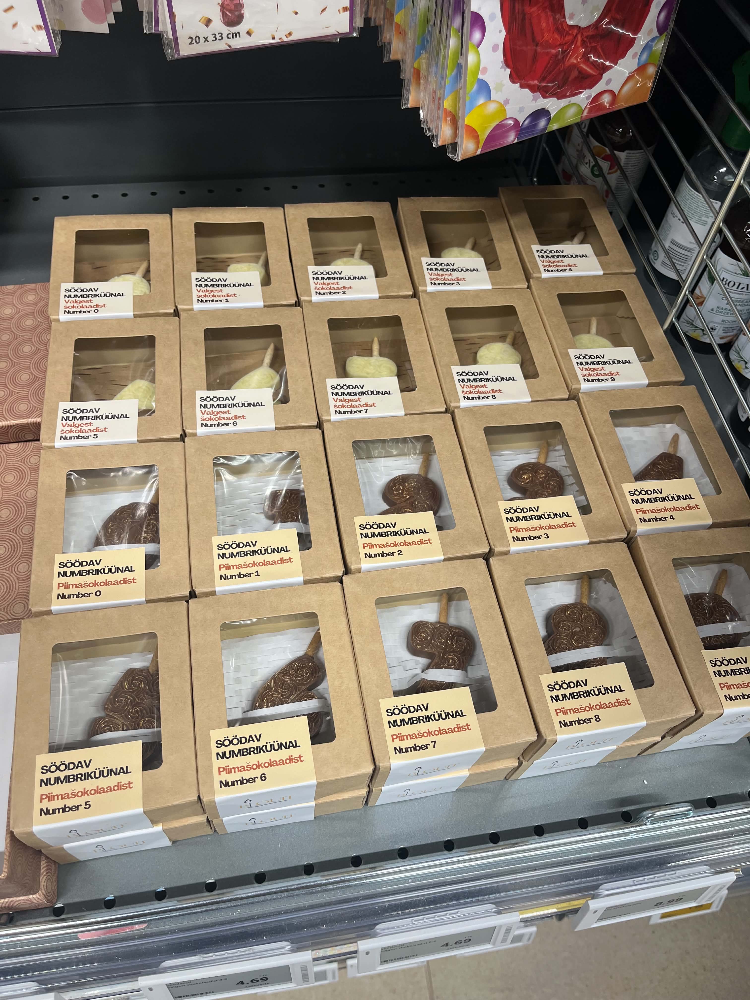 White and brown edible birthday candles are packaged in boxes and displayed on a shop counter.