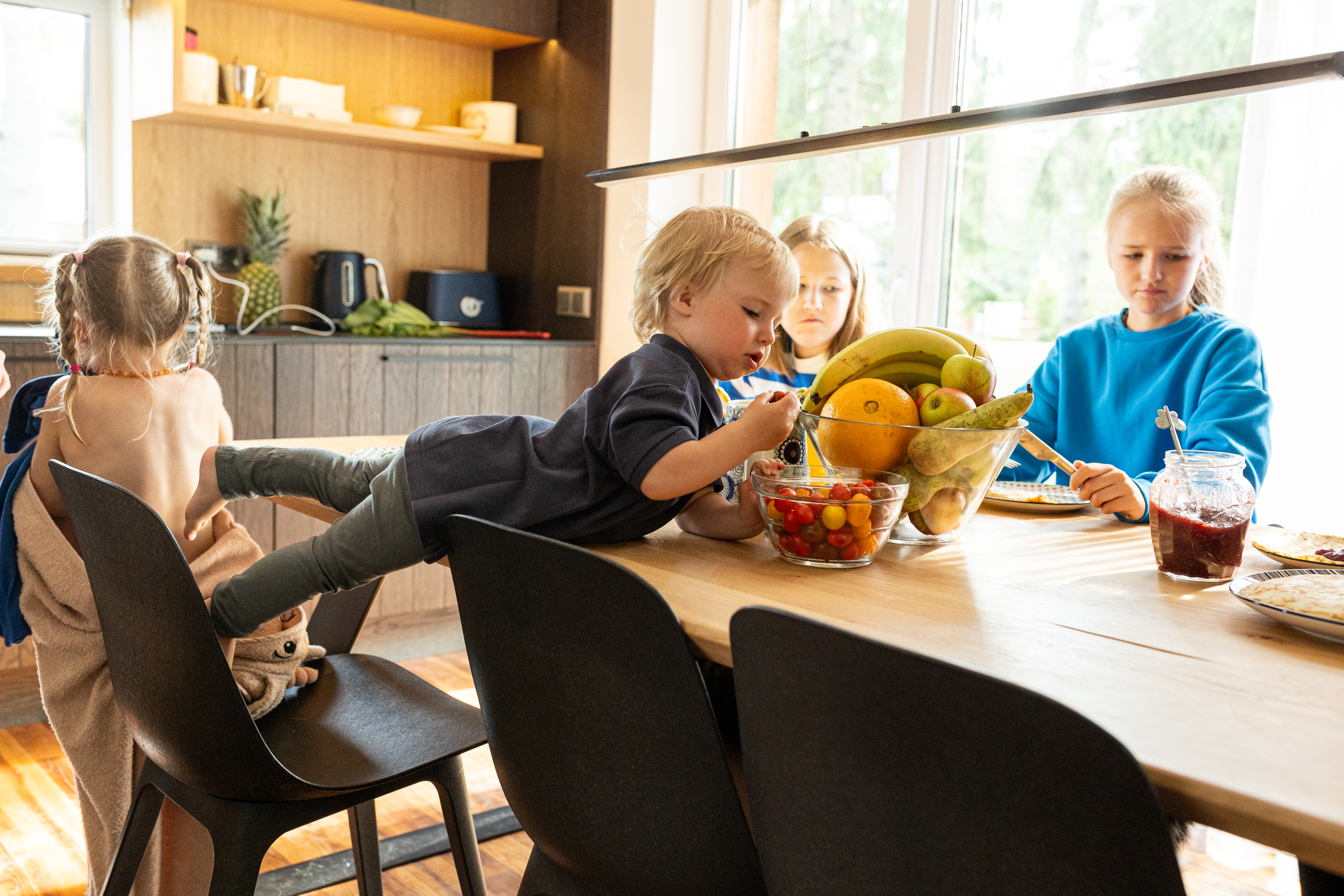 Дети сидят за кухонным столом и завтракают в светлой домашней кухне.
